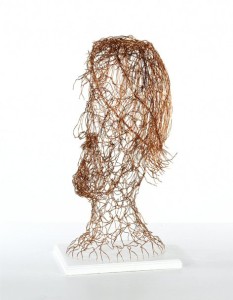 wire head sculpture on white wooden plinth