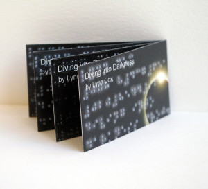 Fan display of Brailled business cards on white plinth