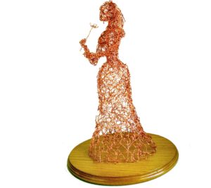 side view of wire lady with flower sculpture on round wooden base
